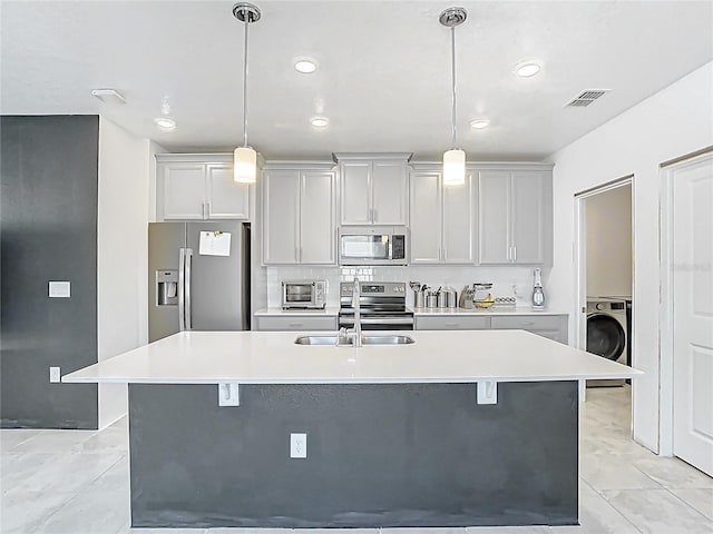 kitchen with light countertops, washer / clothes dryer, a kitchen island with sink, and stainless steel appliances