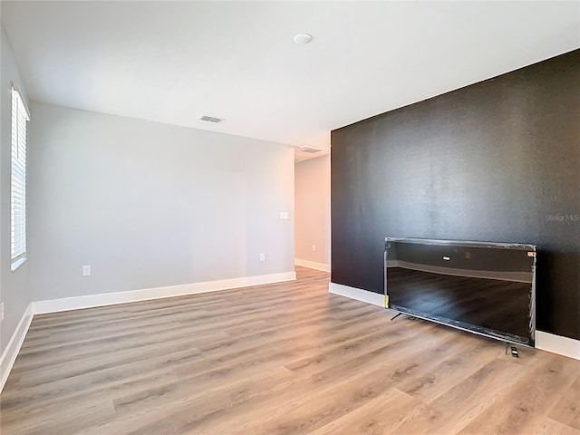 unfurnished room with visible vents, baseboards, and wood finished floors