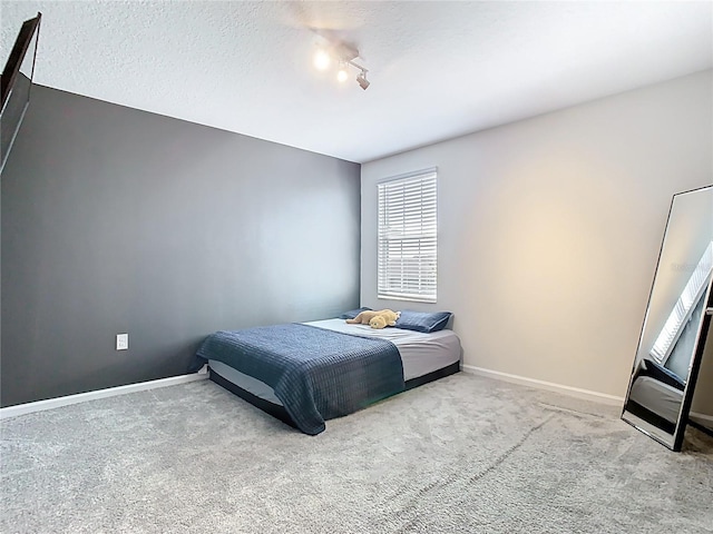 carpeted bedroom featuring baseboards and a textured ceiling