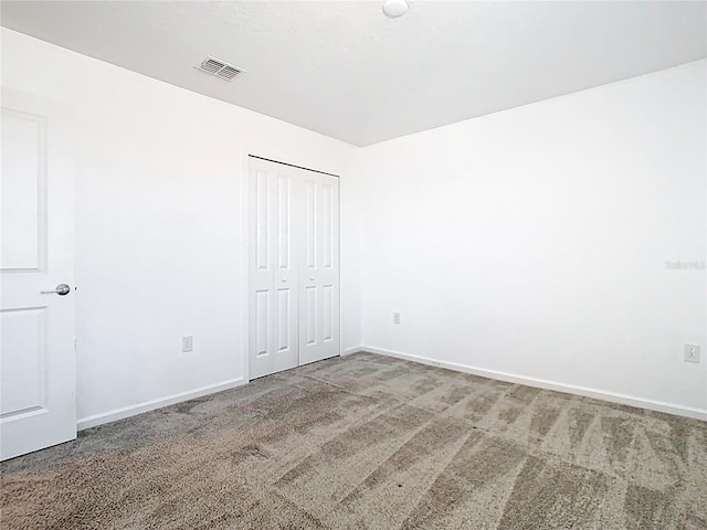 unfurnished bedroom featuring visible vents, baseboards, a closet, and carpet flooring