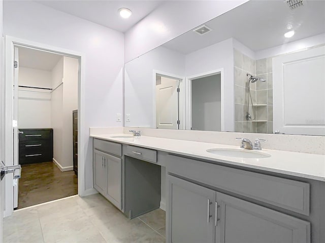 full bathroom with a sink, visible vents, tiled shower, and double vanity