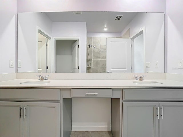 full bathroom featuring a sink, visible vents, double vanity, and a tile shower