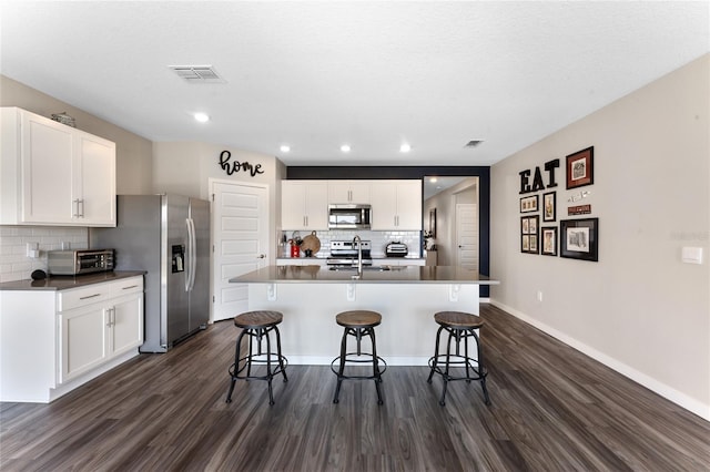 kitchen featuring stainless steel appliances, a kitchen breakfast bar, and dark wood-style flooring