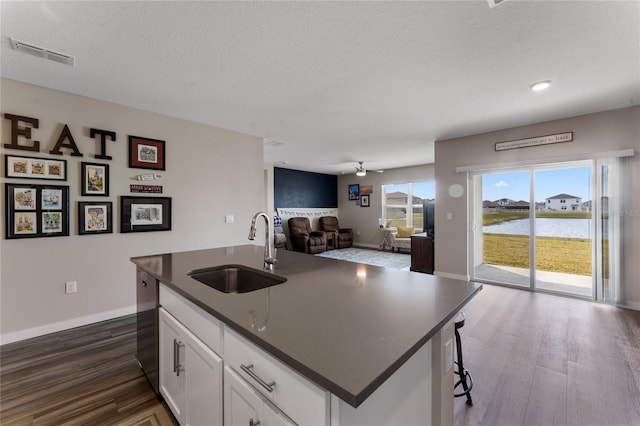 kitchen with dark countertops, dark wood-style floors, visible vents, and a sink