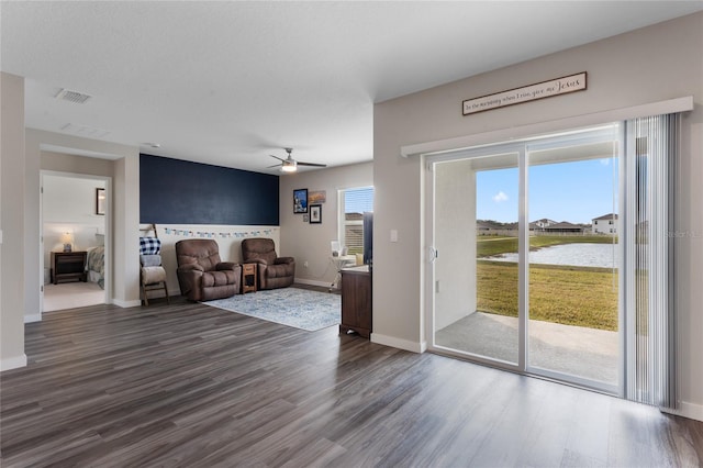 unfurnished living room featuring visible vents, baseboards, ceiling fan, and dark wood-style flooring