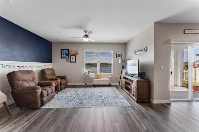 living room with wood finished floors, baseboards, and ceiling fan