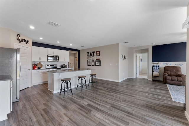 kitchen with visible vents, a breakfast bar, open floor plan, stainless steel appliances, and light wood finished floors