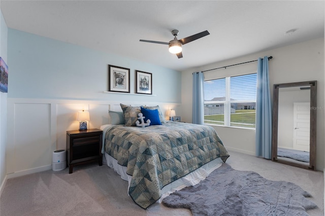 carpeted bedroom with ceiling fan and wainscoting