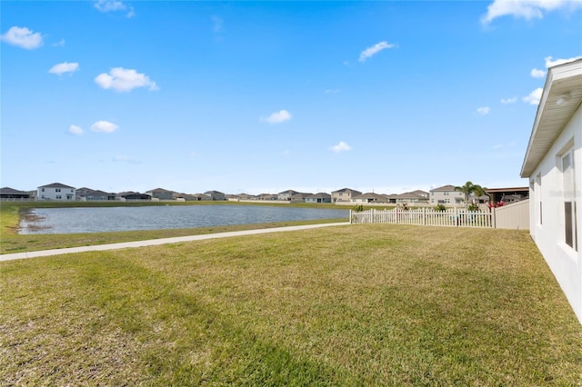 view of yard featuring a residential view, fence, and a water view