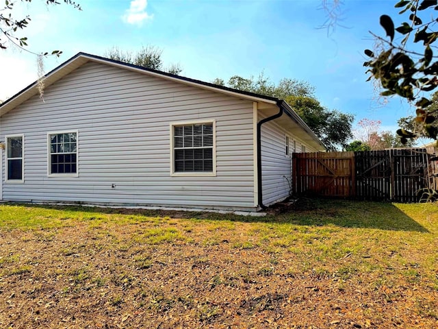 view of side of home with a yard and fence