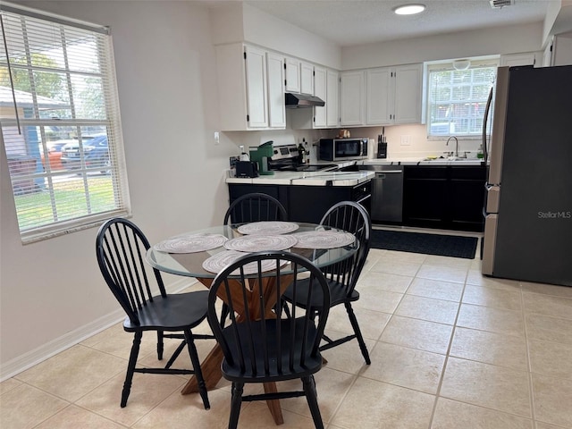 dining area featuring light tile patterned floors, visible vents, a textured ceiling, and baseboards