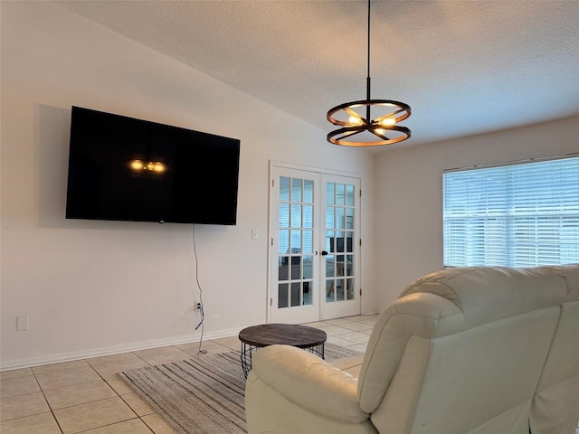 living area with lofted ceiling, light tile patterned flooring, french doors, a textured ceiling, and a notable chandelier