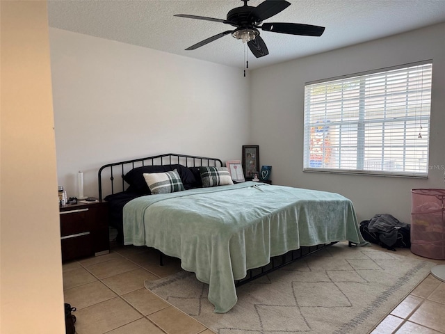 bedroom with light tile patterned floors, a textured ceiling, and a ceiling fan