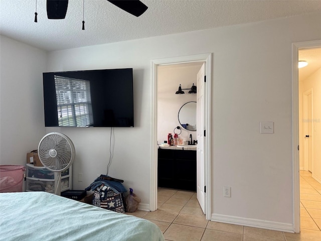 bedroom featuring light tile patterned floors, ensuite bathroom, and a textured ceiling