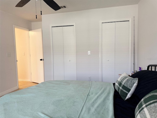 bedroom with light tile patterned flooring, visible vents, and multiple closets