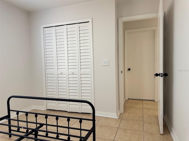 bedroom featuring light tile patterned floors, a closet, and baseboards