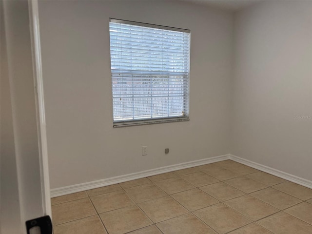 spare room with light tile patterned floors and baseboards