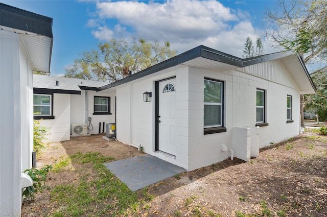 doorway to property featuring concrete block siding and ac unit