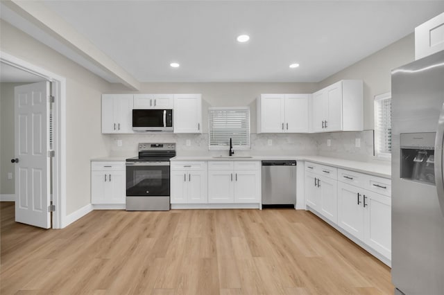 kitchen with plenty of natural light, appliances with stainless steel finishes, light wood-style floors, and a sink