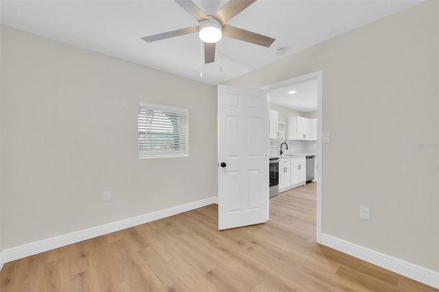 unfurnished room with light wood-style flooring, a ceiling fan, baseboards, and a sink