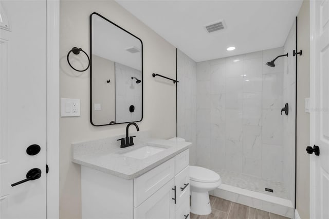 full bath with vanity, wood finished floors, visible vents, a stall shower, and toilet