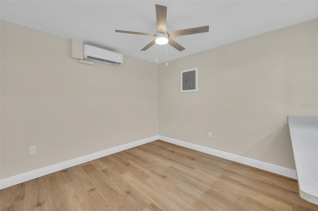 unfurnished room with a wall mounted air conditioner, light wood-style flooring, a ceiling fan, electric panel, and baseboards