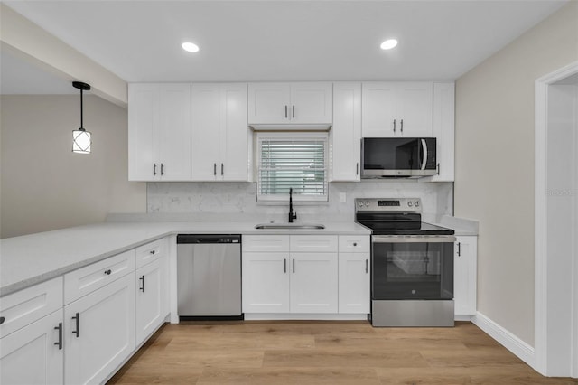 kitchen with a sink, tasteful backsplash, stainless steel appliances, light wood-style floors, and light countertops