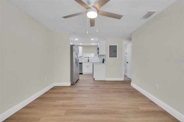 unfurnished living room with visible vents, electric panel, light wood finished floors, baseboards, and ceiling fan