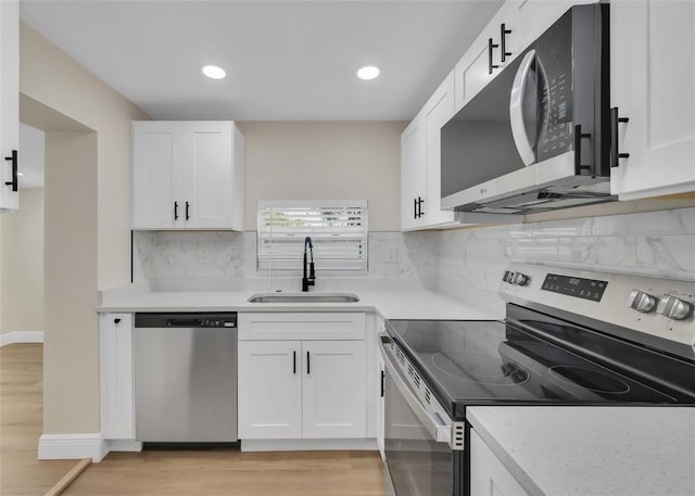 kitchen with a sink, light wood-type flooring, white cabinetry, and stainless steel appliances