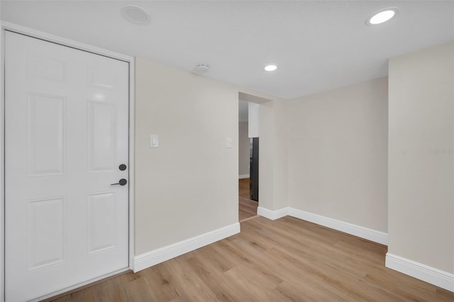 spare room featuring recessed lighting, light wood-style floors, and baseboards