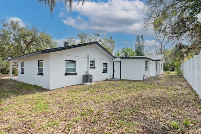 rear view of property with fence, a lawn, and central AC