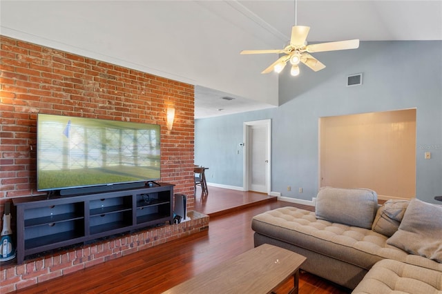 living room with a ceiling fan, wood finished floors, visible vents, baseboards, and a towering ceiling