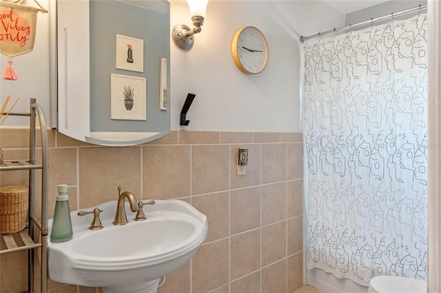 full bathroom with a sink, toilet, tile walls, and wainscoting