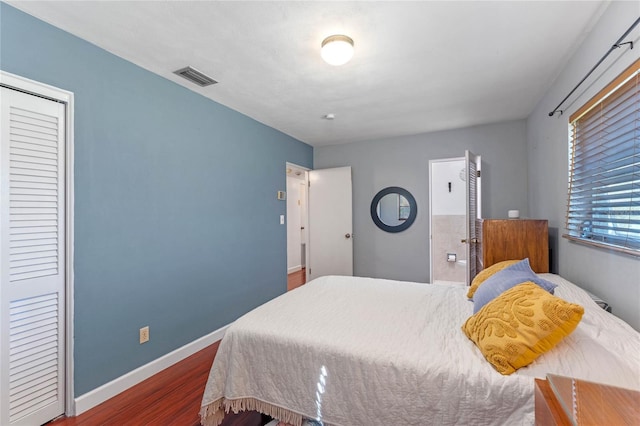 bedroom with a closet, visible vents, baseboards, and wood finished floors