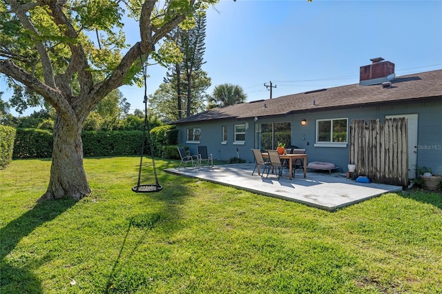 rear view of house with a patio, a chimney, and a yard