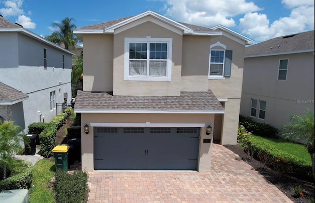 view of front facade with a shingled roof and stucco siding