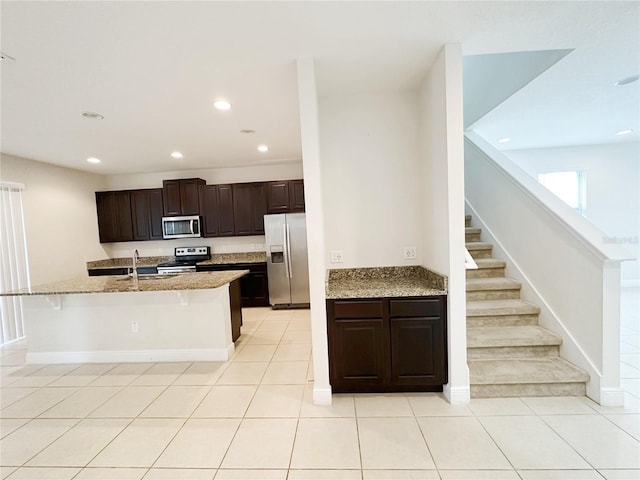 kitchen featuring dark brown cabinets, light tile patterned floors, recessed lighting, appliances with stainless steel finishes, and a sink