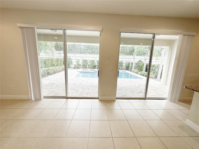 doorway with light tile patterned floors and baseboards