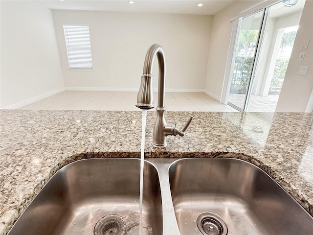 interior details featuring recessed lighting, baseboards, stone counters, and a sink