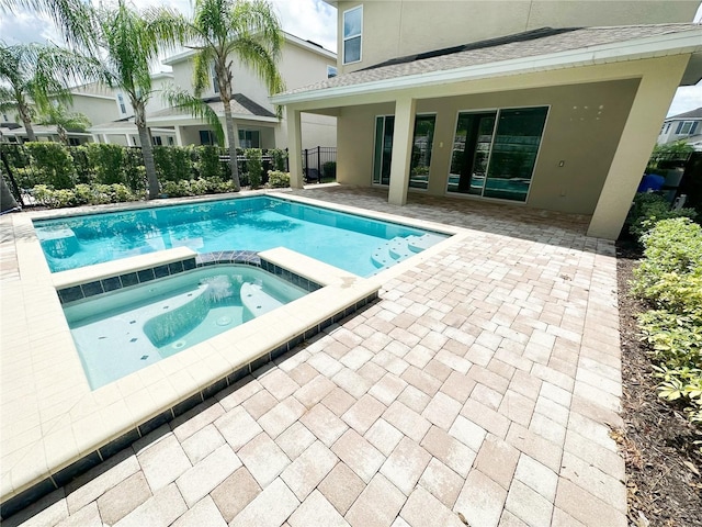 view of swimming pool with a patio area, fence, and a pool with connected hot tub