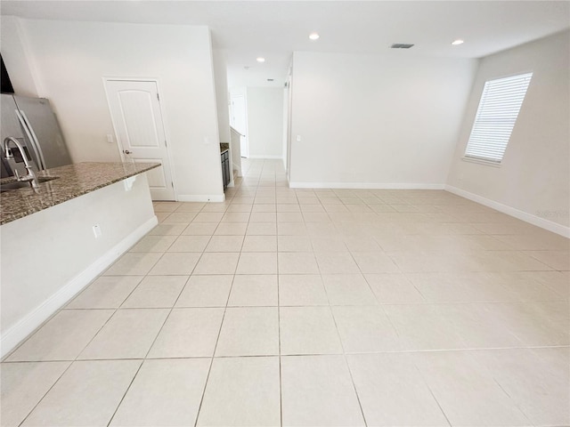 unfurnished living room featuring a sink, baseboards, light tile patterned flooring, and recessed lighting