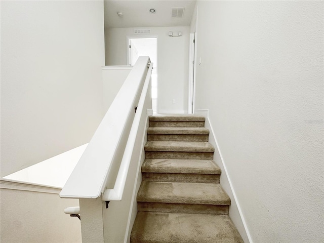 stairway with visible vents, baseboards, and carpet floors