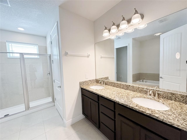 bathroom featuring a garden tub, a sink, a textured ceiling, a shower stall, and tile patterned flooring