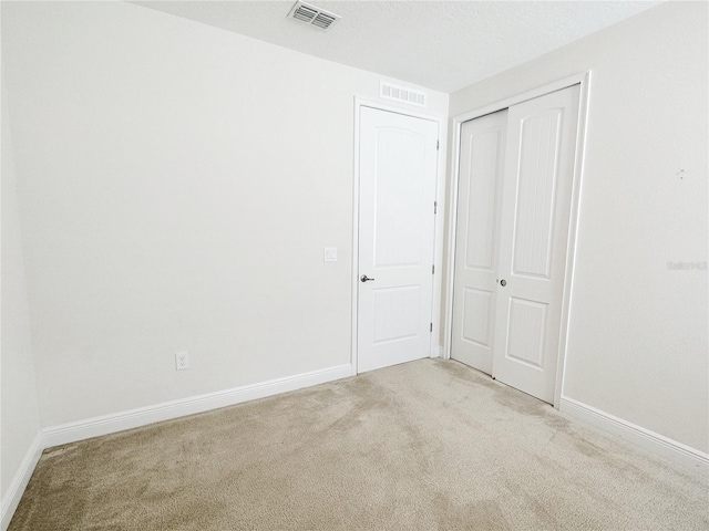 unfurnished bedroom with visible vents, light colored carpet, and baseboards