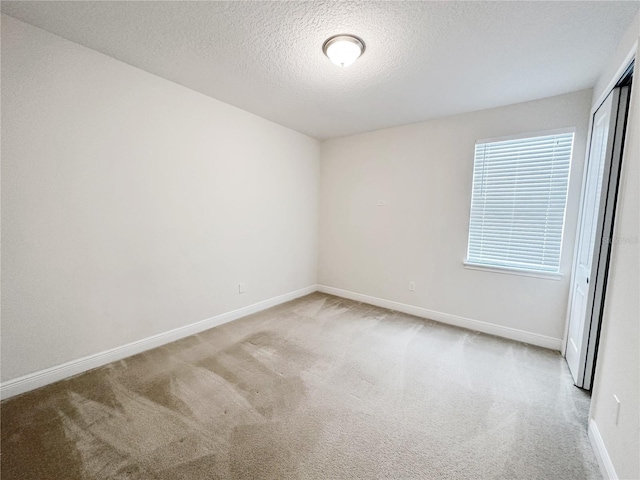 carpeted spare room with baseboards and a textured ceiling