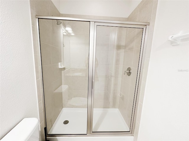 bathroom featuring a shower stall and toilet