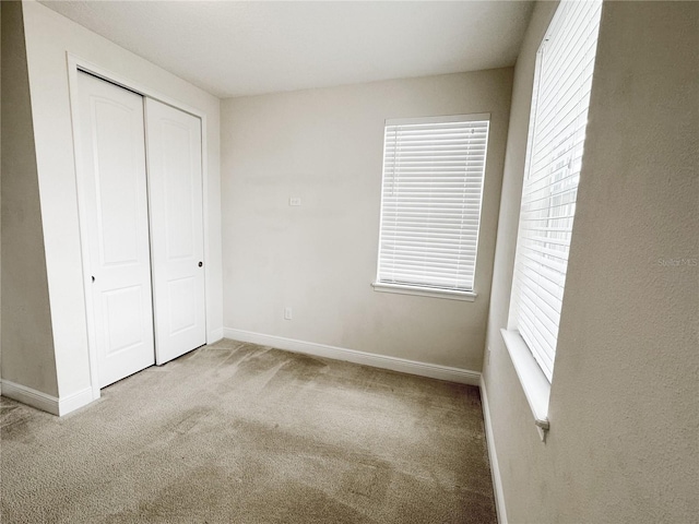 unfurnished bedroom with a closet, baseboards, and carpet flooring