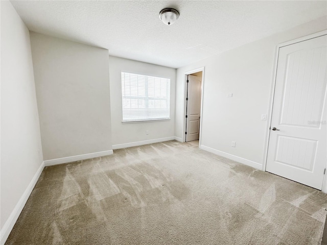 carpeted empty room with baseboards and a textured ceiling