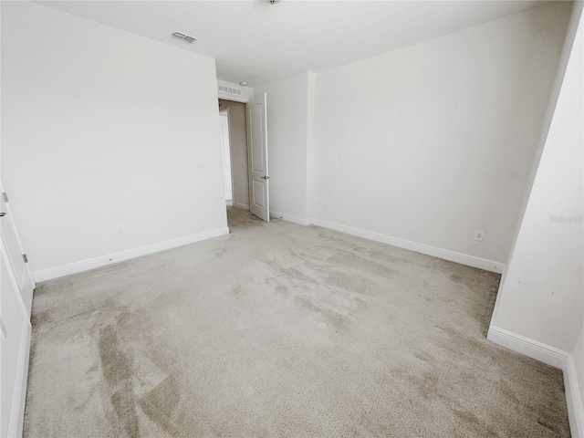 carpeted empty room featuring visible vents and baseboards