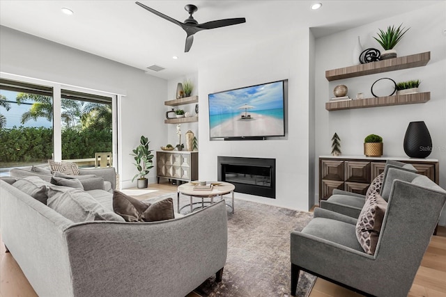 living area featuring wood finished floors, visible vents, a ceiling fan, recessed lighting, and a glass covered fireplace